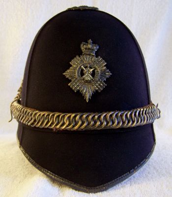 Midlothian Constabulary Victorian Chained Helmet
Midlothian Constabulary Victorian Chained Helmet, blue cloth covered cork helmet in four panels (no front or rear seams), blackened thistle top, helmet plate, thistle pattern ear rosettes and chin chain with seperate hook at rear to allow the chain to be worn across the helmet body. Cloth centre band with leather edging and leather chin strap for normal use - the chin chain appears to have never been worn in the 'down' position as it is slightly twisted where it is restrained by the hook of the right hand ear rosette to ensure it fits tightly across the helmet. Single air vent either side
Keywords: midlothian helmet headwear