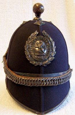 Montgomeryshire Police Chained Helmet, circa 1910
Montgomeryshire Police Chained Helmet, circa 1910, six panel design with black leather centre band, blackened brass ball top with cross base, ear rosettes with chinchain hooked up at rear and helmet plate. Ink handwritten label inside "Montgomery PC28 Humphrey"
Keywords: montgomeryshire helmet chained headwear