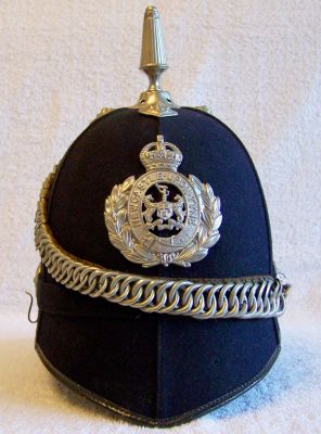 Newcastle Upon Tyne Senior Officers Helmet, Early 1930's
Newcastle Upon Tyne Senior Officers Helmet, Early 1930's, six panel design with cloth centre band, white metal reeded spike and cross base, ear rosettes and graduated link chinchain and helmet plate. Helmet plate is the smaller type with two holes shown on the garter after the word 'Tyne'. This plate was introduced in the early 1930's. Early paper label for Christys inside.
Keywords: newcastle helmet Headwear