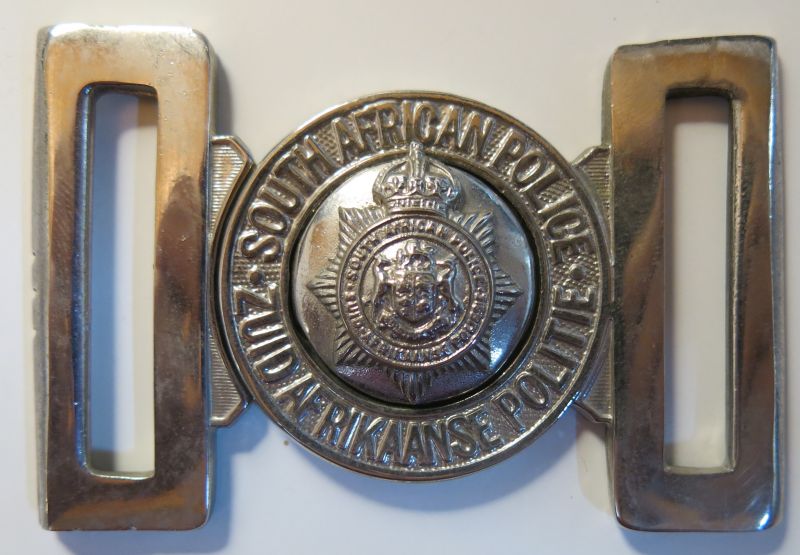 South African Police Non European Belt Buckle worn 1913 to 1926 (and later)
Non-European members of the SA Police wore their insignia in White Metal or chrome plated until 1977 when insignia was made the same for all regardless of race. 

The official second language of the Union of South Africa from 1910 was Dutch which changed to Afrikaans in 1925. The following year the Police officially changed their insignia replacing the words Zuid Afrikaanse Politie with the words Suid Afrikaanse Poliesie. It took many years for this to filter down to the lower ranks with photos in existence from the 1940s showing members still wearing old Dutch language items.
Keywords: South African Police Non European Belt Buckle 1913 to 1926